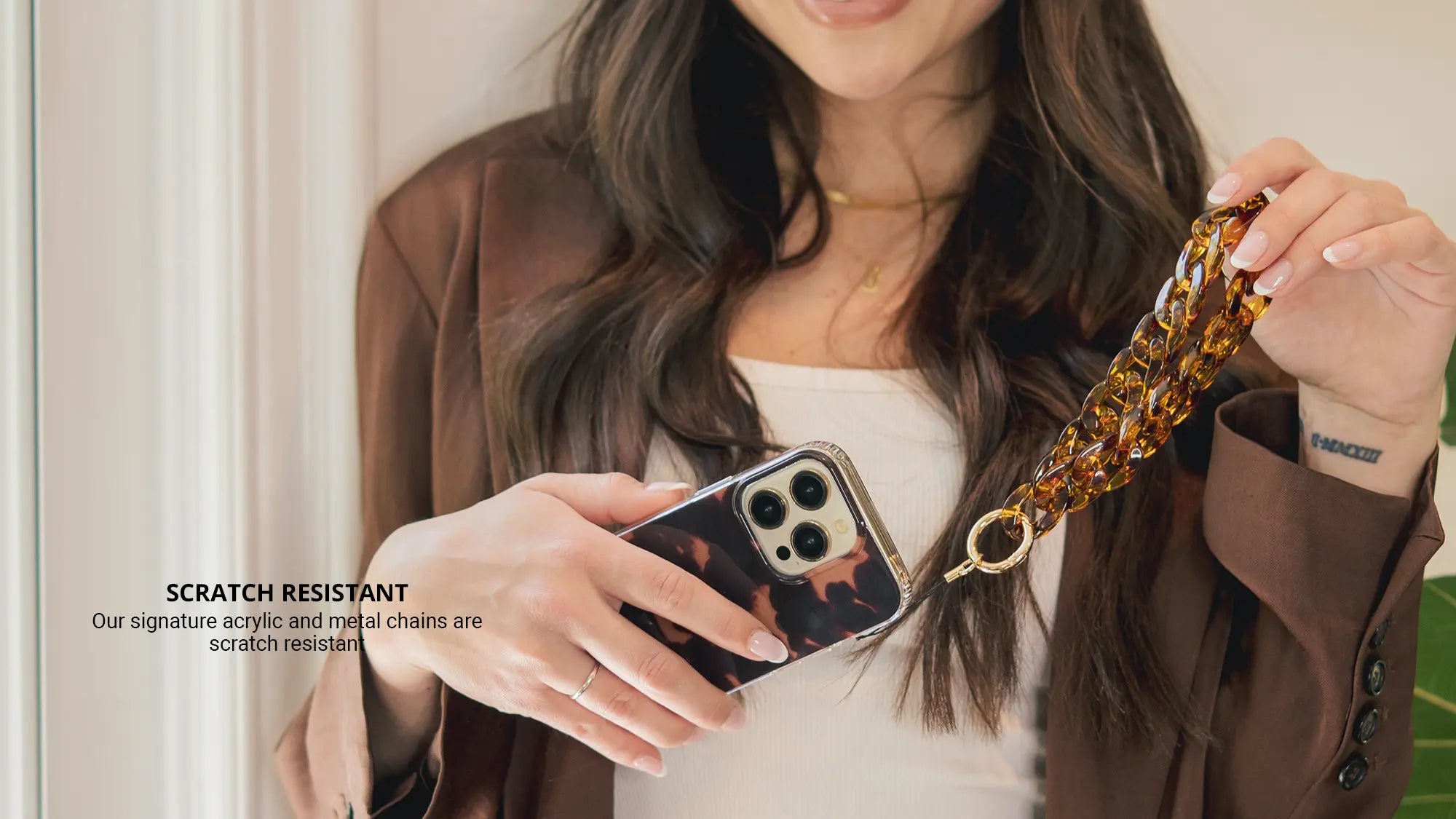 Tortoiseshell Phone Wristlet Charm while wearing brown jacket