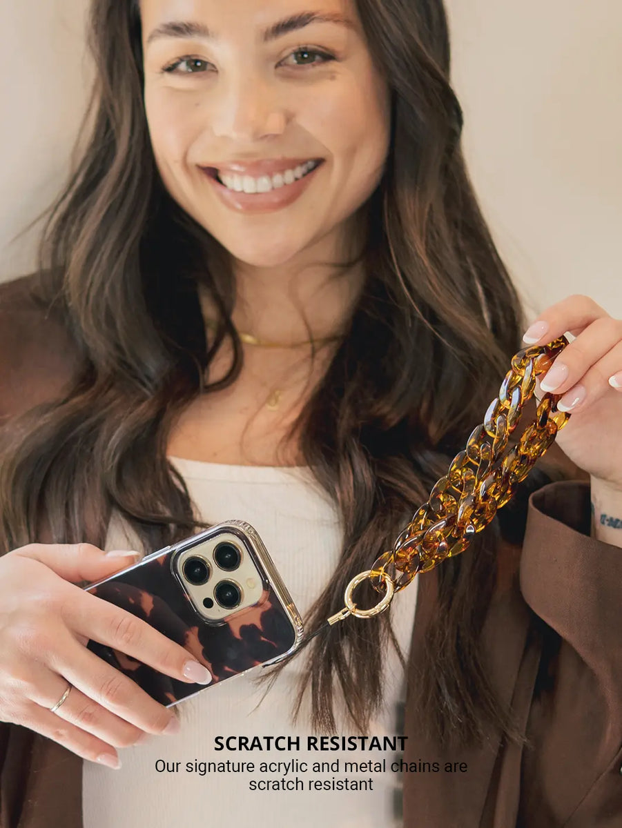 Tortoiseshell Phone Wristlet Charm while wearing brown jacket