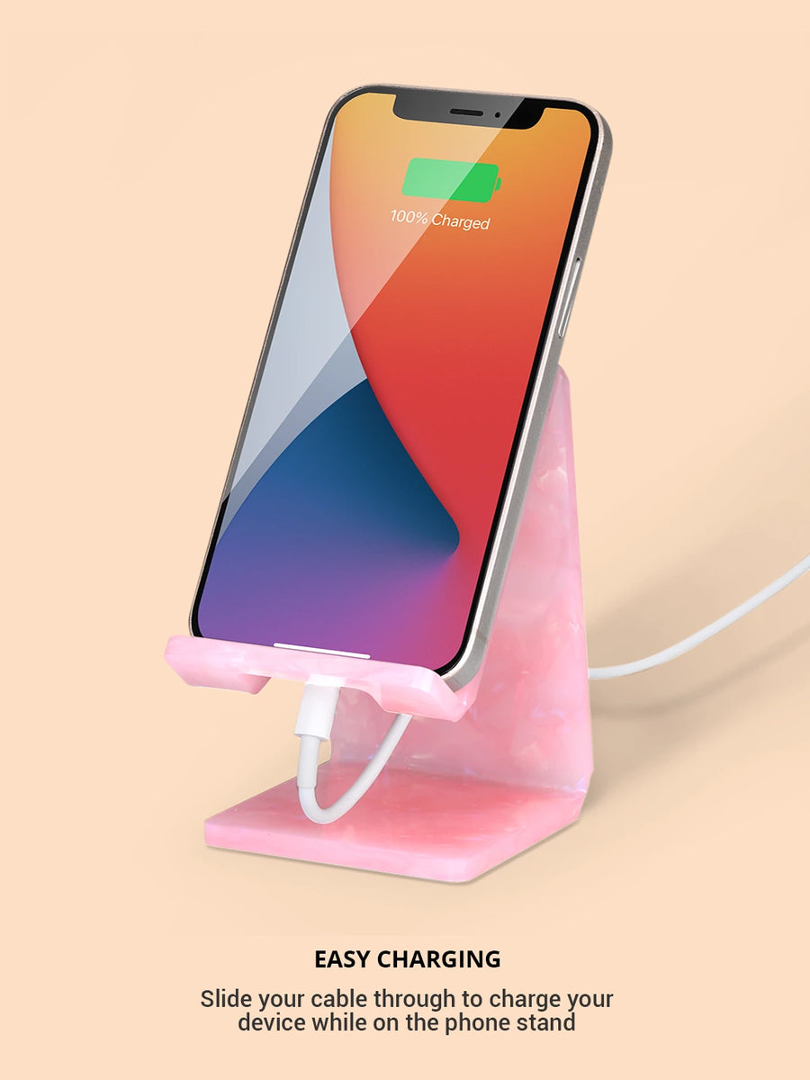 Showing the rose quartz phone and tablet stand with an iPhone charging via a white USB cable