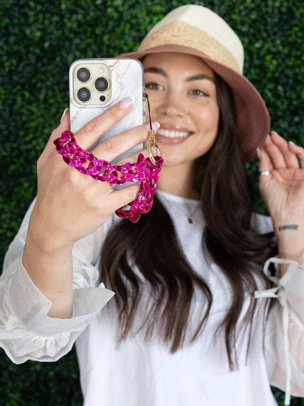 Taking selfie from an iPhone with hot pink clear holographic phone charm wristlet 