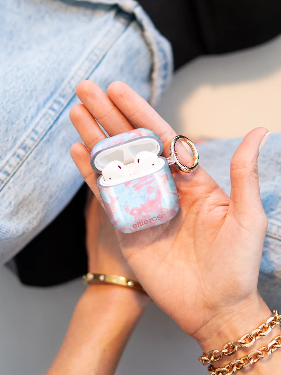 Pink and blue Tie Dye Airpods Case opening with gold ring on hand