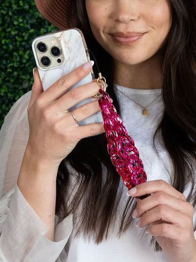 Expanded Hot pink  holographic phone charm wristlet showing metal gold ring on finger connected to iPhone