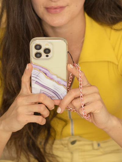 Taking a picture using iPhone latched Rose gold phone wristlet  charm on hands wearing yellow shirt and yellow jeans