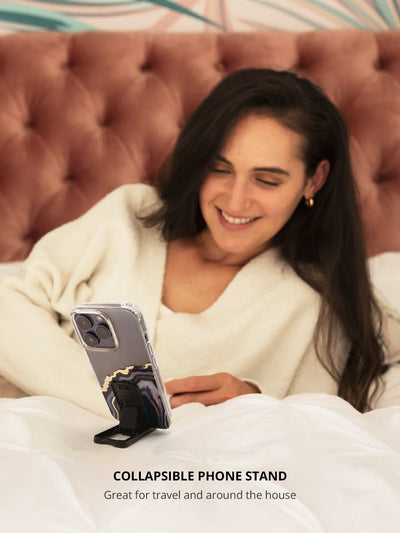 Black collapsible phone stand with an iPhone while on bed