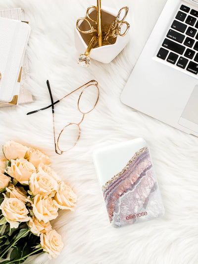 Rose gold agate powerbank on table together with laptop flowers and glasses