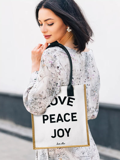 Wearing market tote bag on shoulder wearing black and white dress love peace joy design
