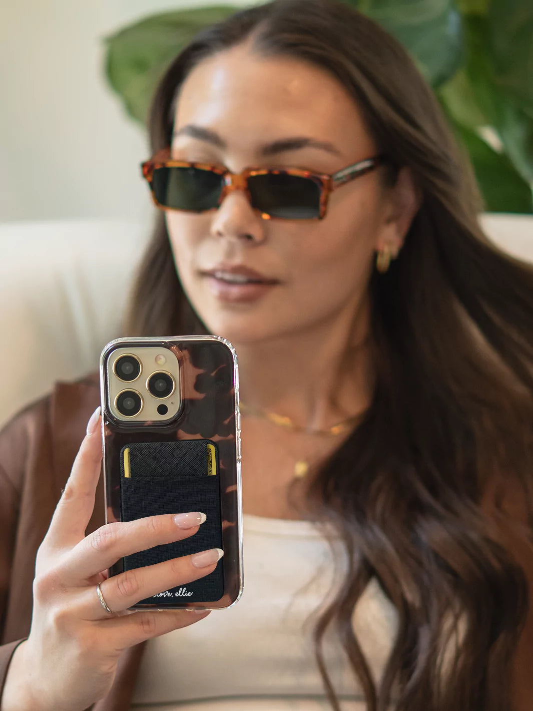 Black Stick on Phone Pocket attached to iPhone case wearing sunglasses and white top