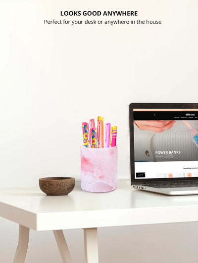 Pink Onyx pen cup with colorful pens and a laptop