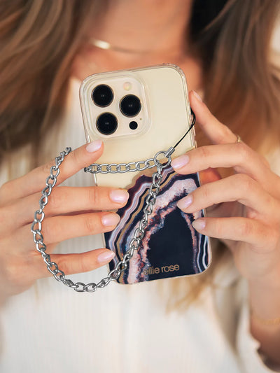 Showing gunmetal phone wristlet charm and iPhone with black agate wearing blue jeans and white top with white background