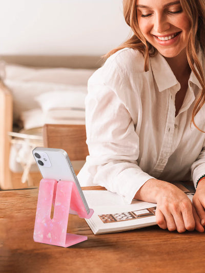 Rose Quartz phone stand with black iPhone on a brown table