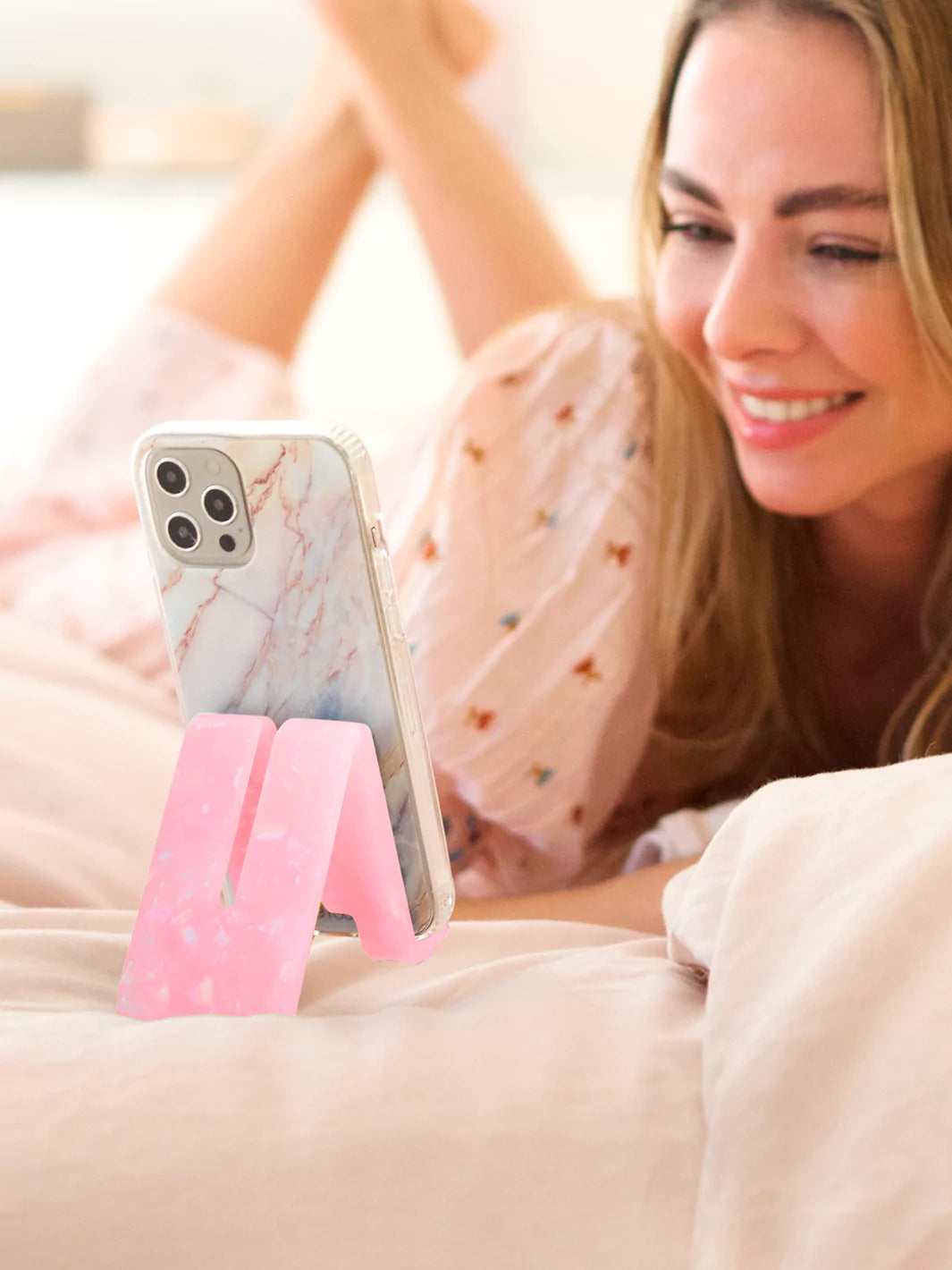 Rose Quartz phone stand with iPhone case while on bed