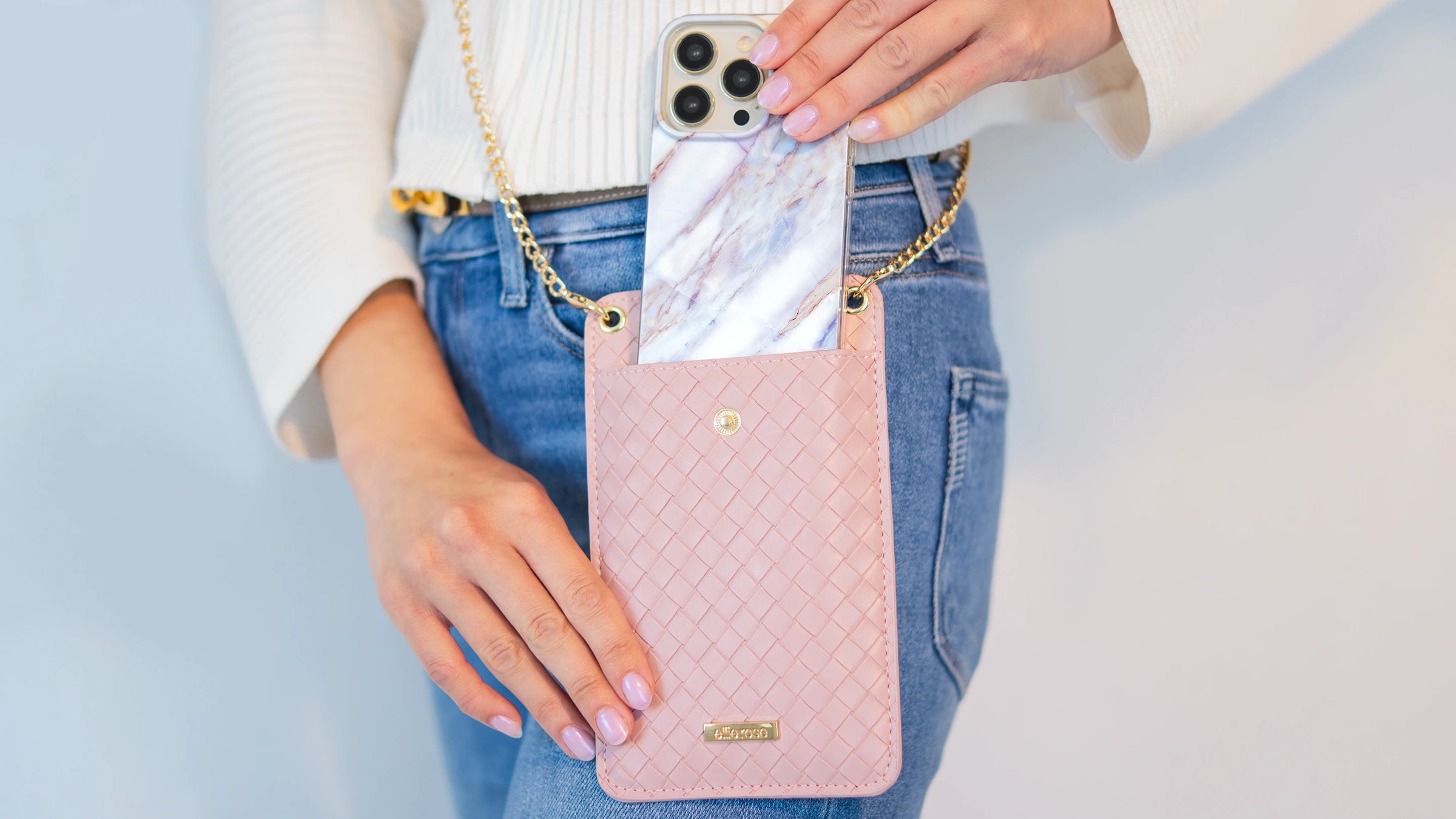 Showing blush crossbody phone bag while putting an iphone