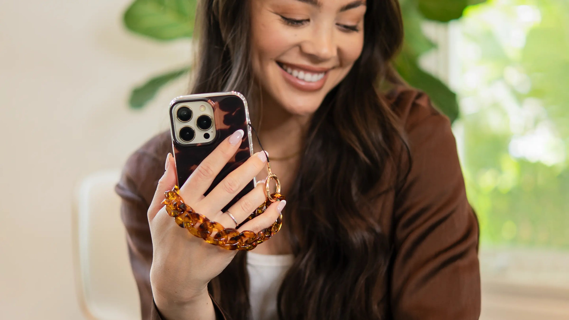 Holding a tortoiseshell phone wristlet charm 