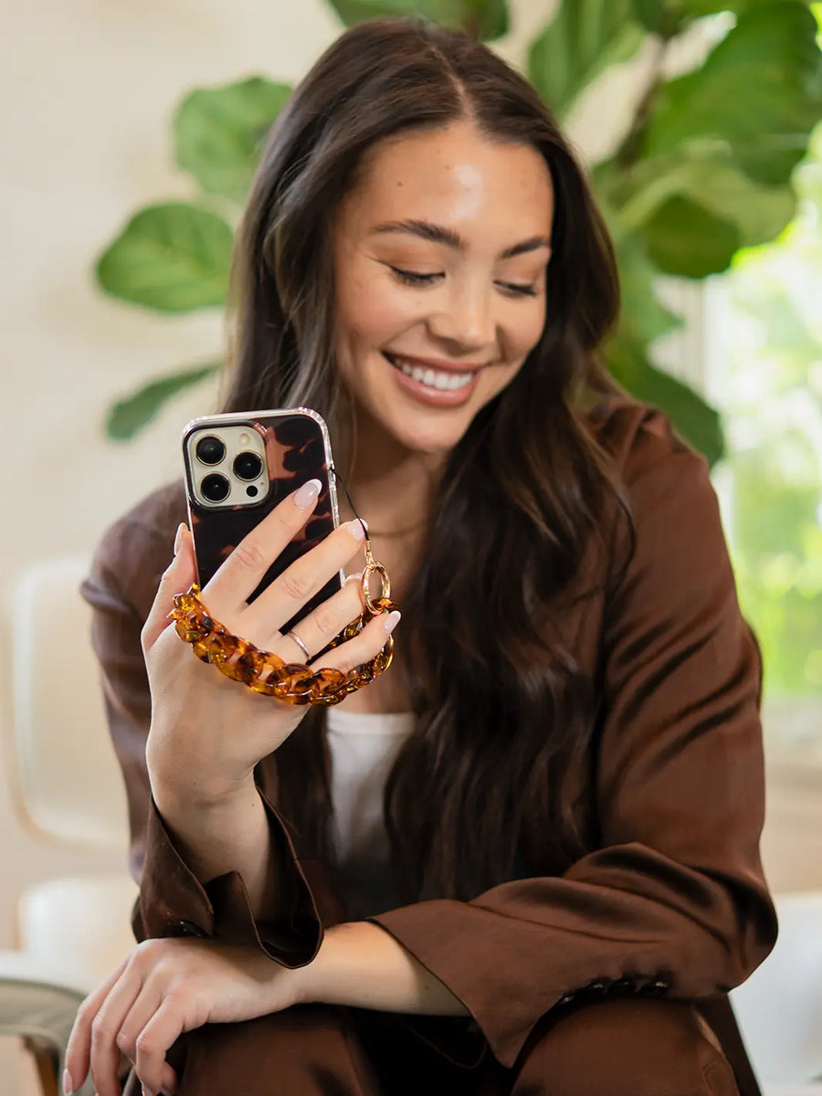 Holding a tortoiseshell phone wristlet charm on portrait