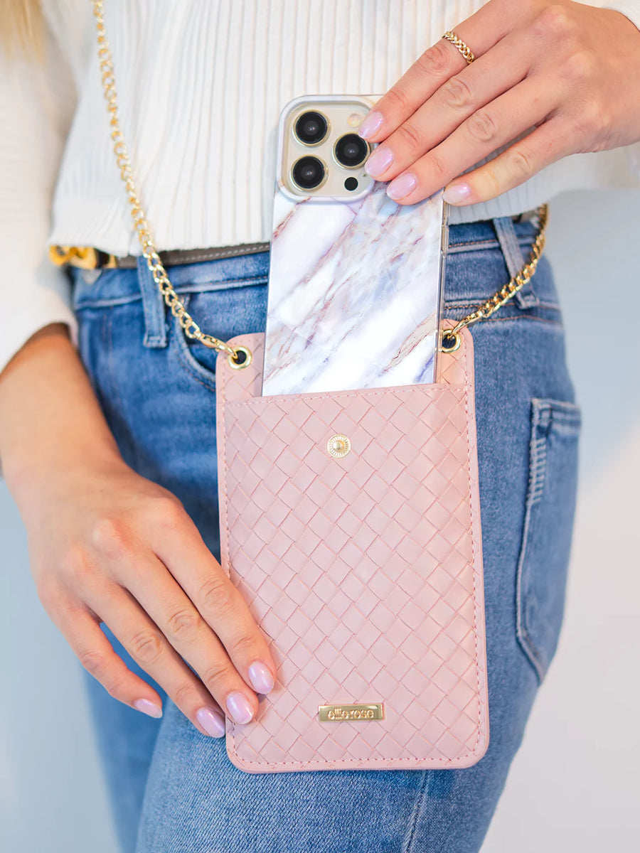 Showing blush crossbody phone bag while putting an iphone